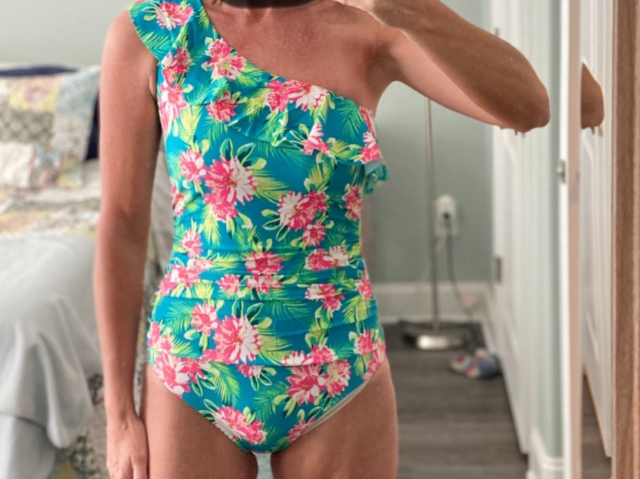 close up of woman wearing bright colored floral should swimsuit in mirror