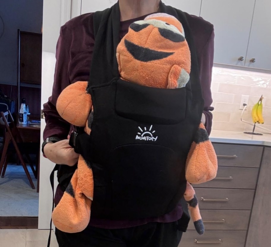 a woman wearing a baby carrier with a stuffed tigger as passenger