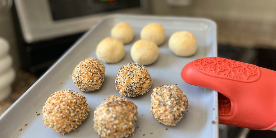 hand holding sheet pan with bagel bites on top