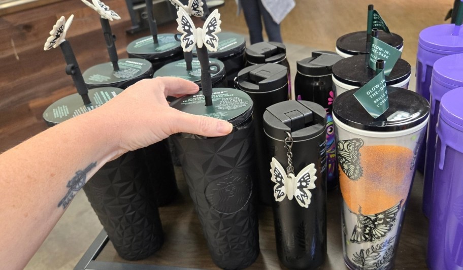 womans hand reaching for a cold cup with moth straw topper