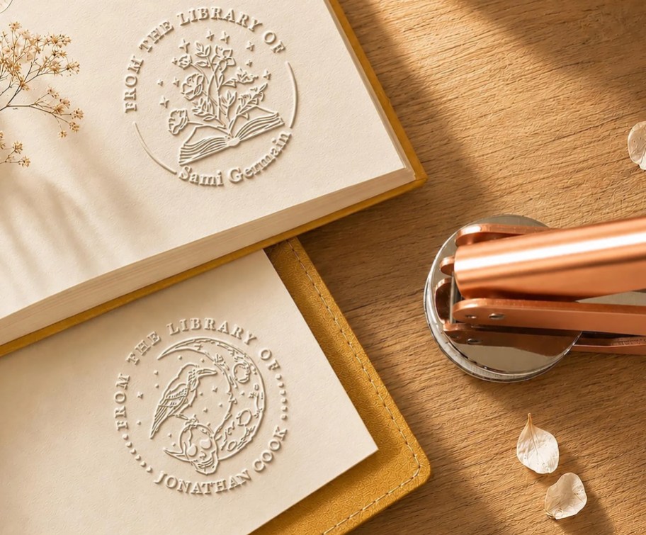 Rose gold book embosser on wood table with embossed pages