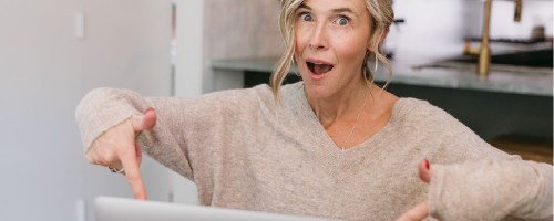 woman pointing at macbook laptop with excited expression
