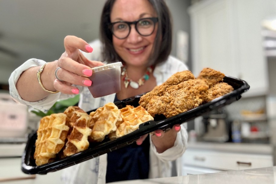 woman holding chicken and waffles and hot honey
