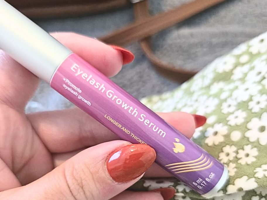 purple eyelash serum container in hand