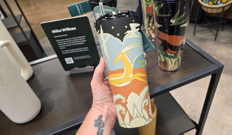 womans hand holding a deco inspired mike wilcox collab tumbler
