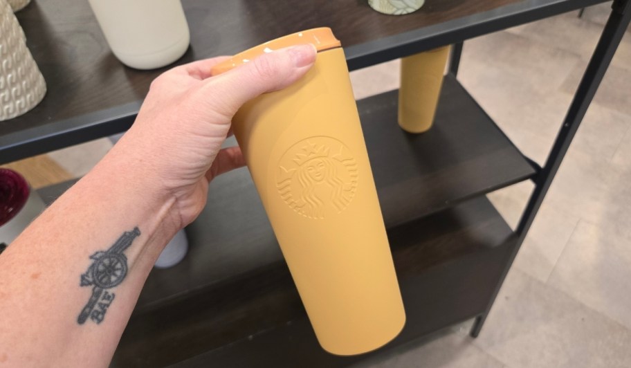 womans hand holding golden tumbler