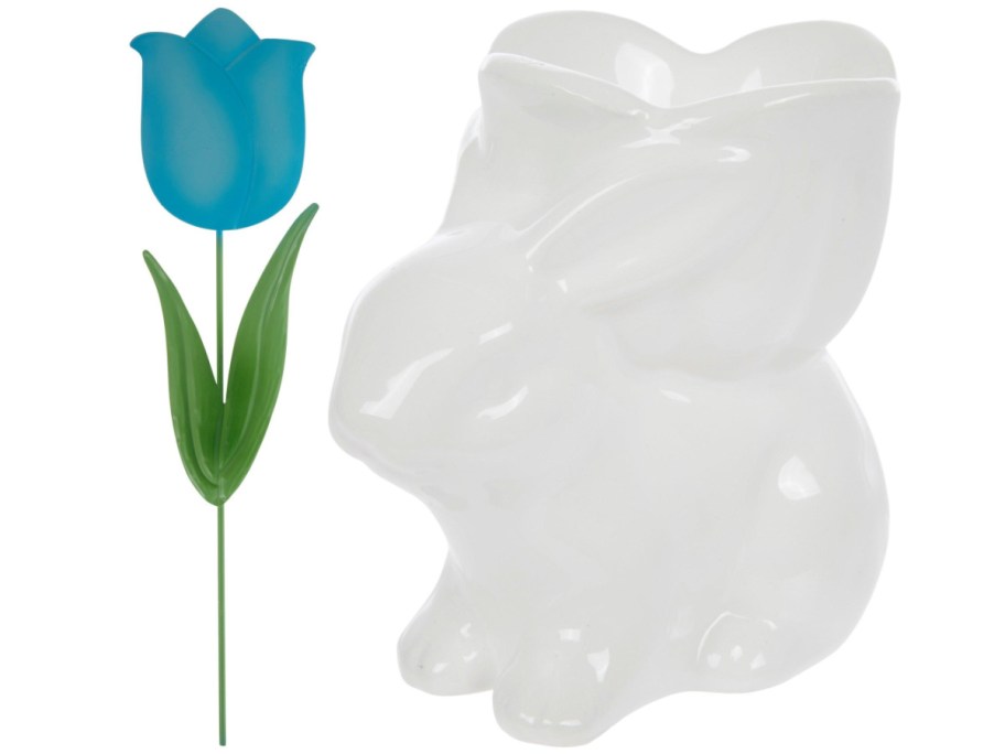 White ceramic rabbit-shaped vase beside a vibrant blue tulip with green leaves.