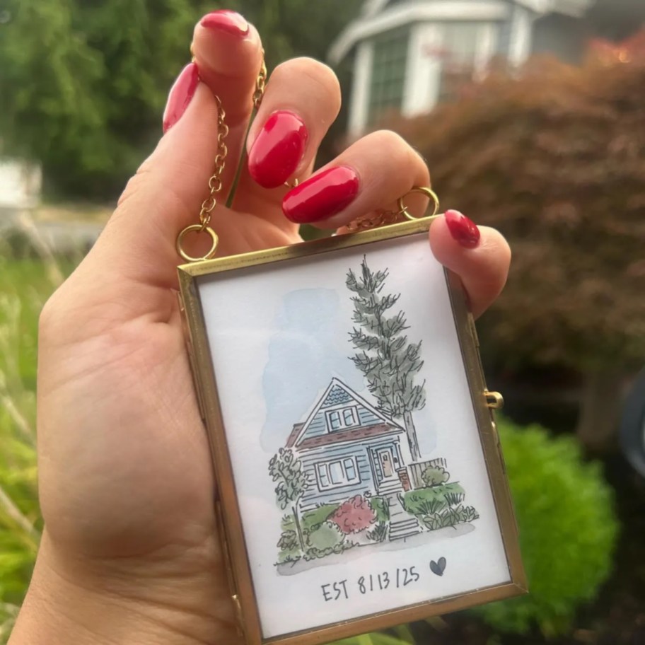 Hand holding a custom house ornament in a gold frame