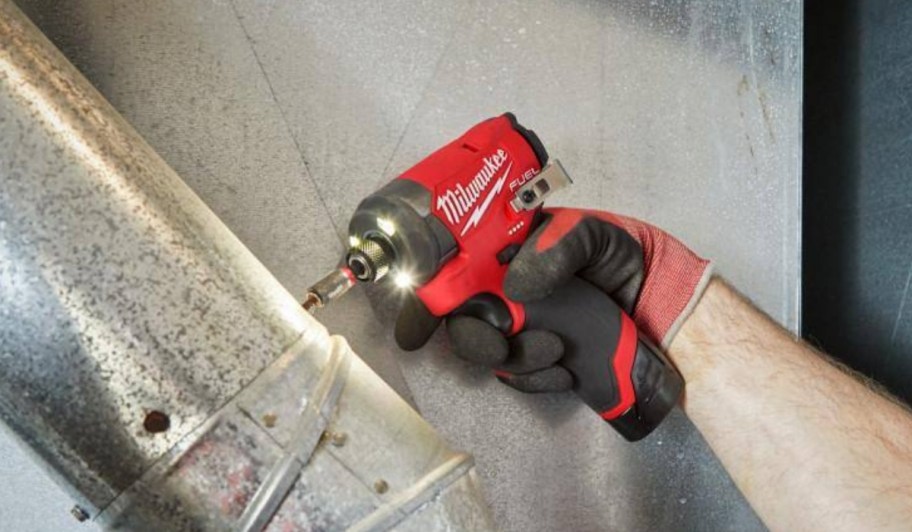 a mans hand holding and using an impact driver