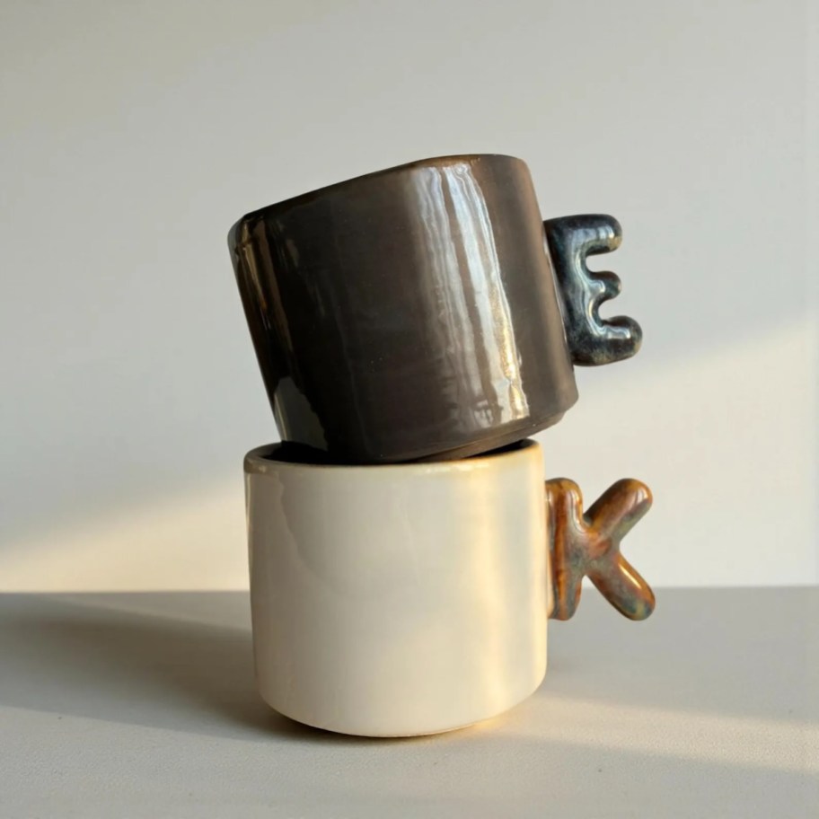 black and cream colored initial mugs stacked together