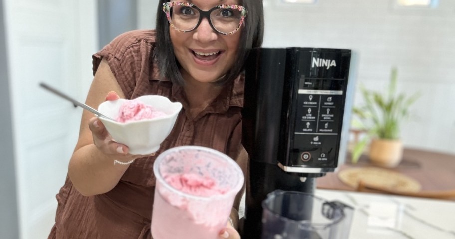 woman holding a bowl of pink ice cream next to ninja creami