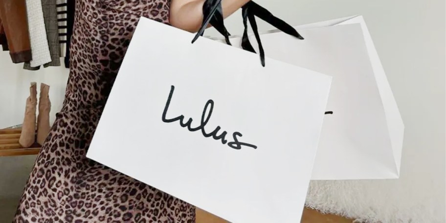 person holding two white lulus bags