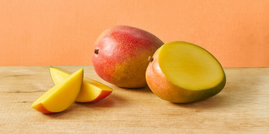 two mangos on table with one cut 