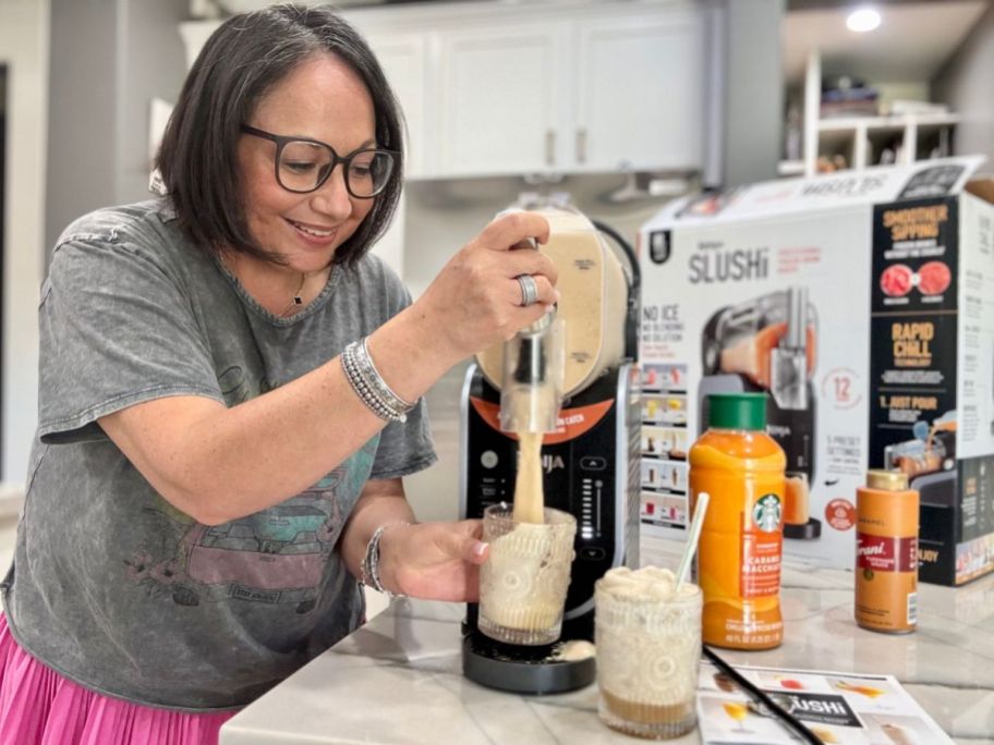 A woman in a kitchen making a slushie with a machine