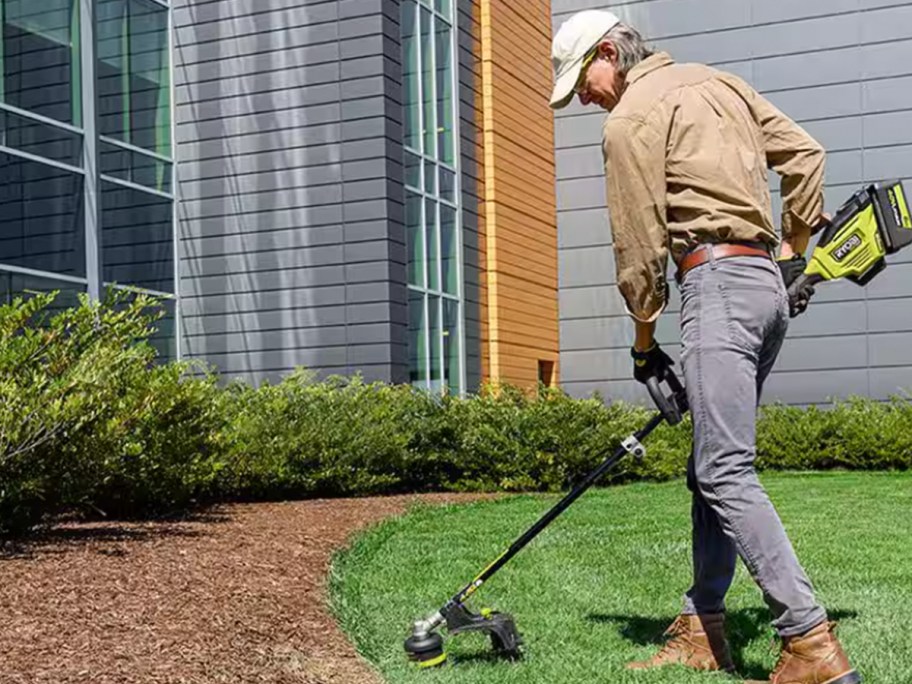 man using ryobi trimmer on grass
