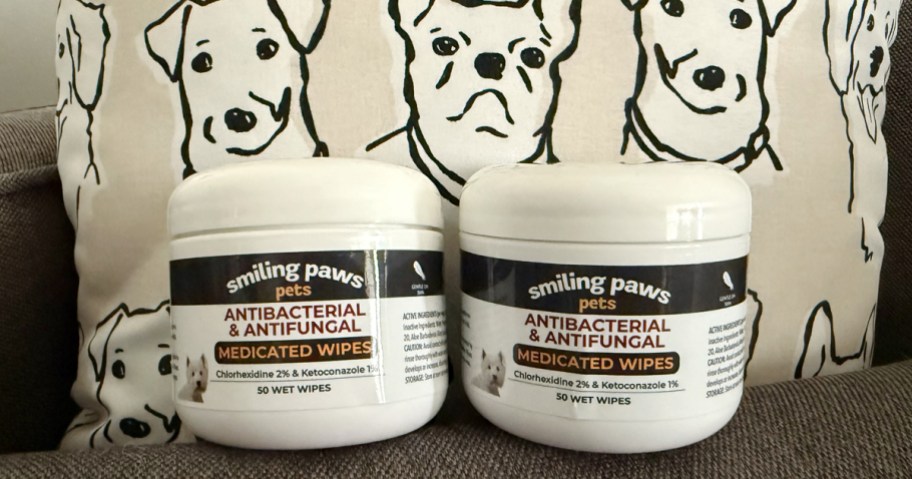 two containers of pet wipes in front of a dog print pillow