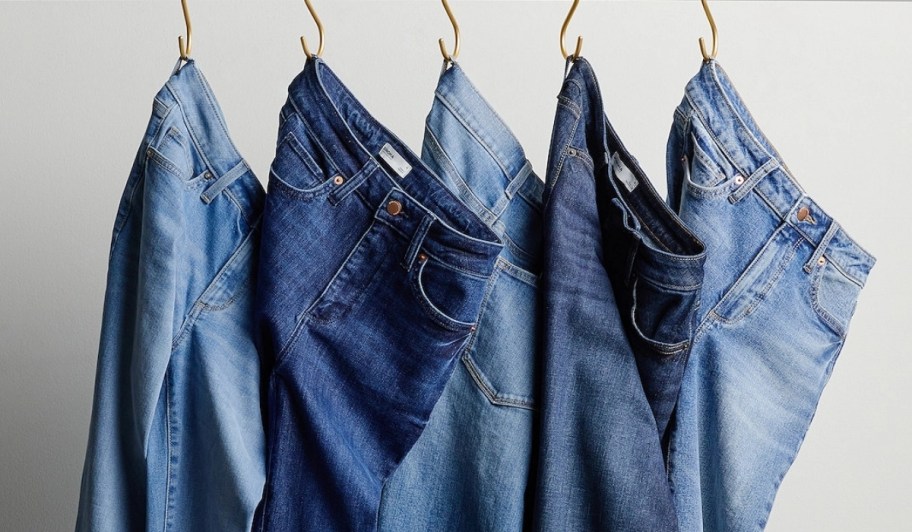 five pair of jeans in different washes hanging from S-hooks