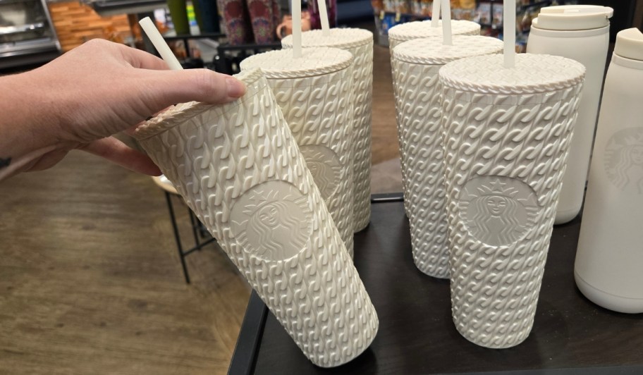 womans hand reaching for a white cable knit textured tumbler