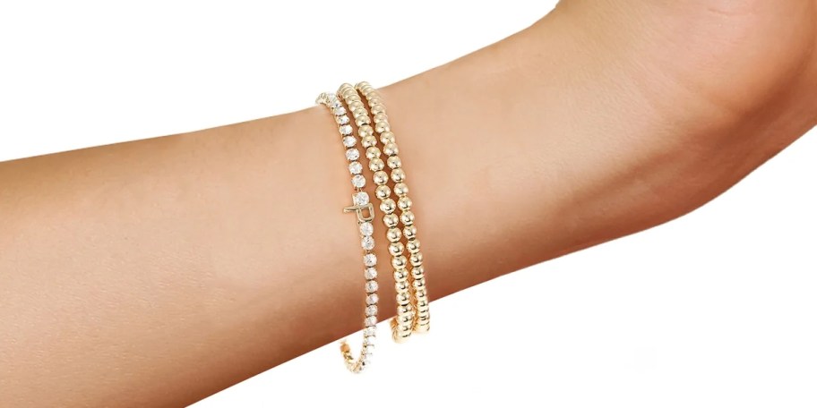 three gold bracelets on wrist