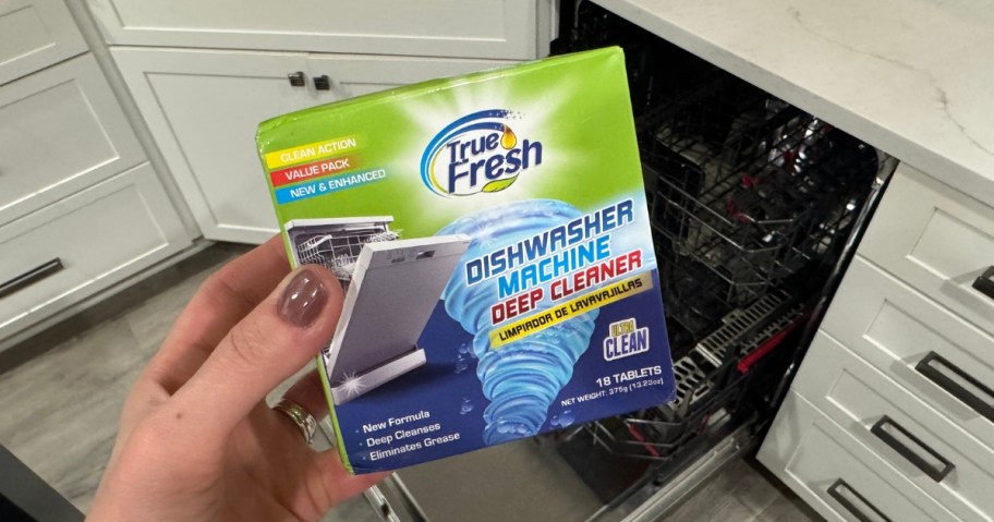 True Fresh dishwasher cleaning tabs box in a woman's hand above a dishwasher