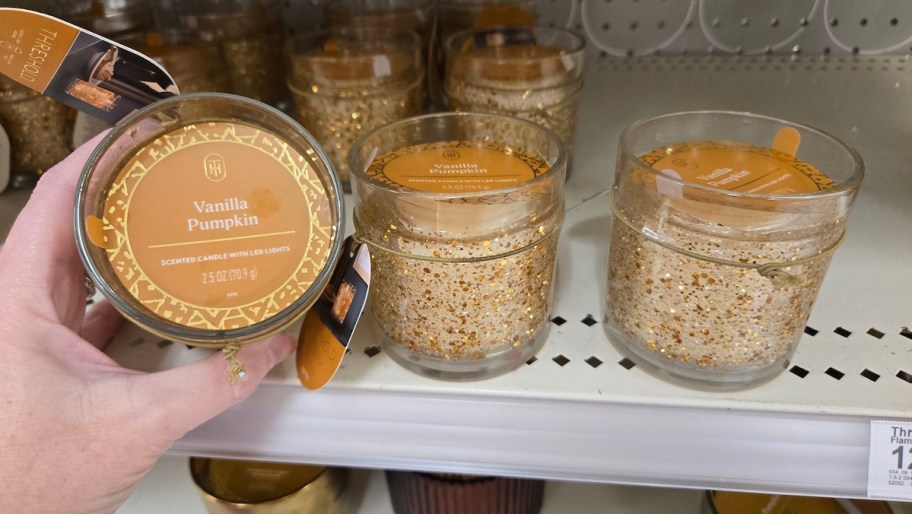 hand holding vanilla pumpkin led candle on store shelf