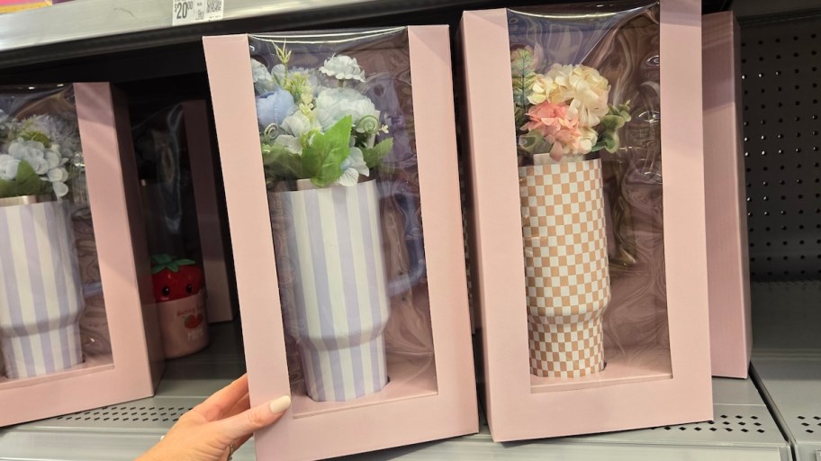 hand holding a box with stripe tumbler with flowers in box on store shelf