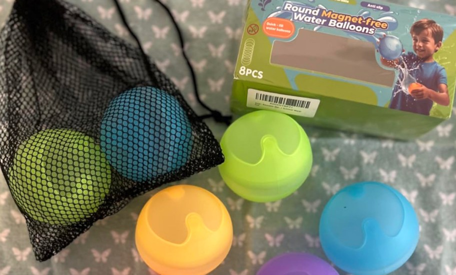 different colored water balloons with black mesh bag on floor