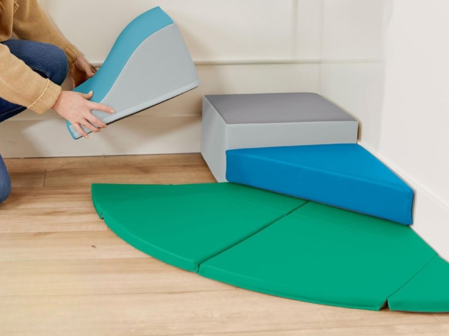 mom putting pieces together on a baby soft mat climber set