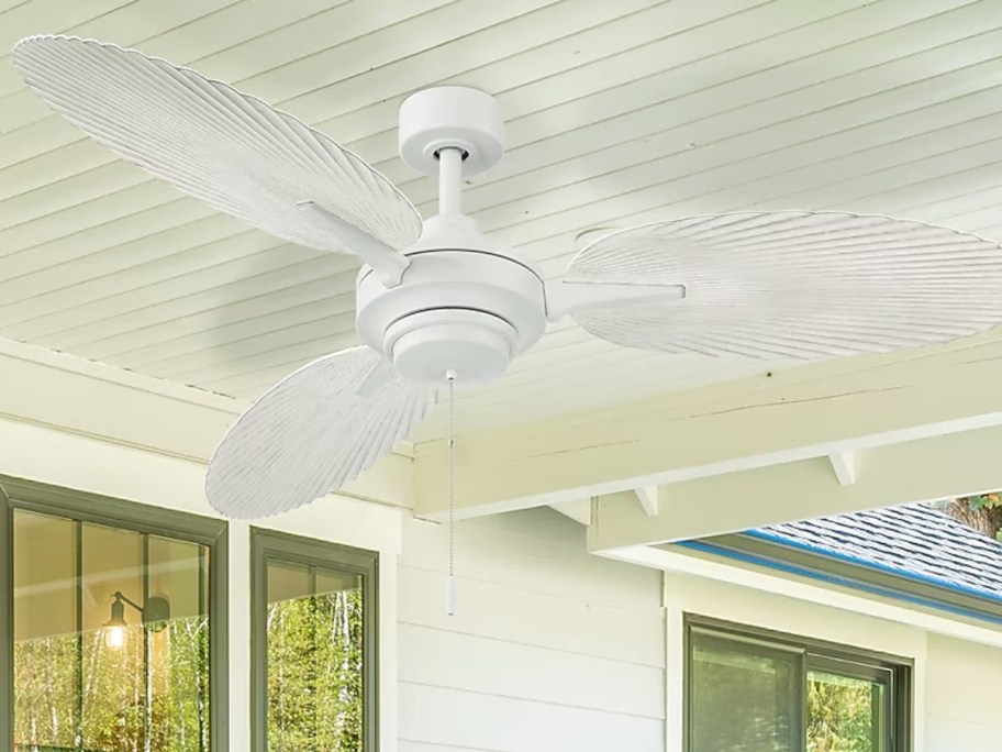 a white palm leaf style outdoor ceiling fan on a porch