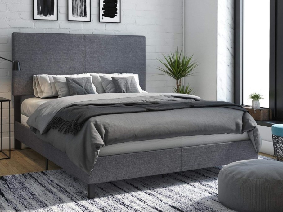 a grey upholstered platform bed with headboard in a bedroom
