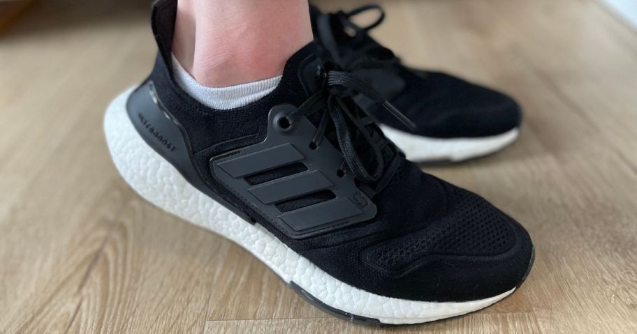 Women's feet wearing black adidas Ultraboost running shoes