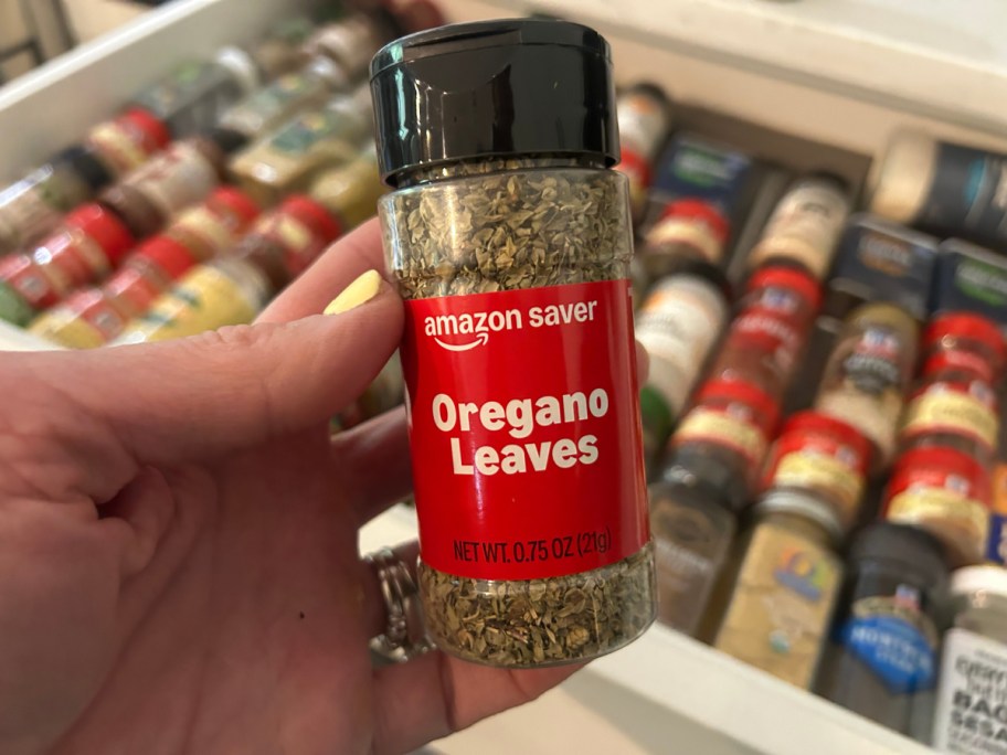 Person holding a bottle of Amazon saver oregano leaves