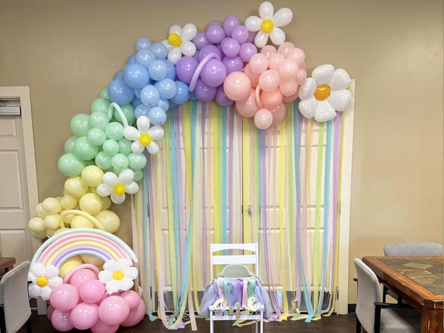 pastel balloon arch over a doorway with streamers