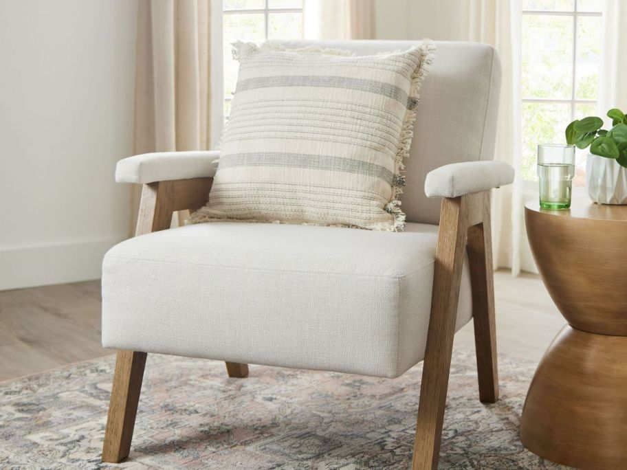 beige accent chair with throw pillow displayed on it