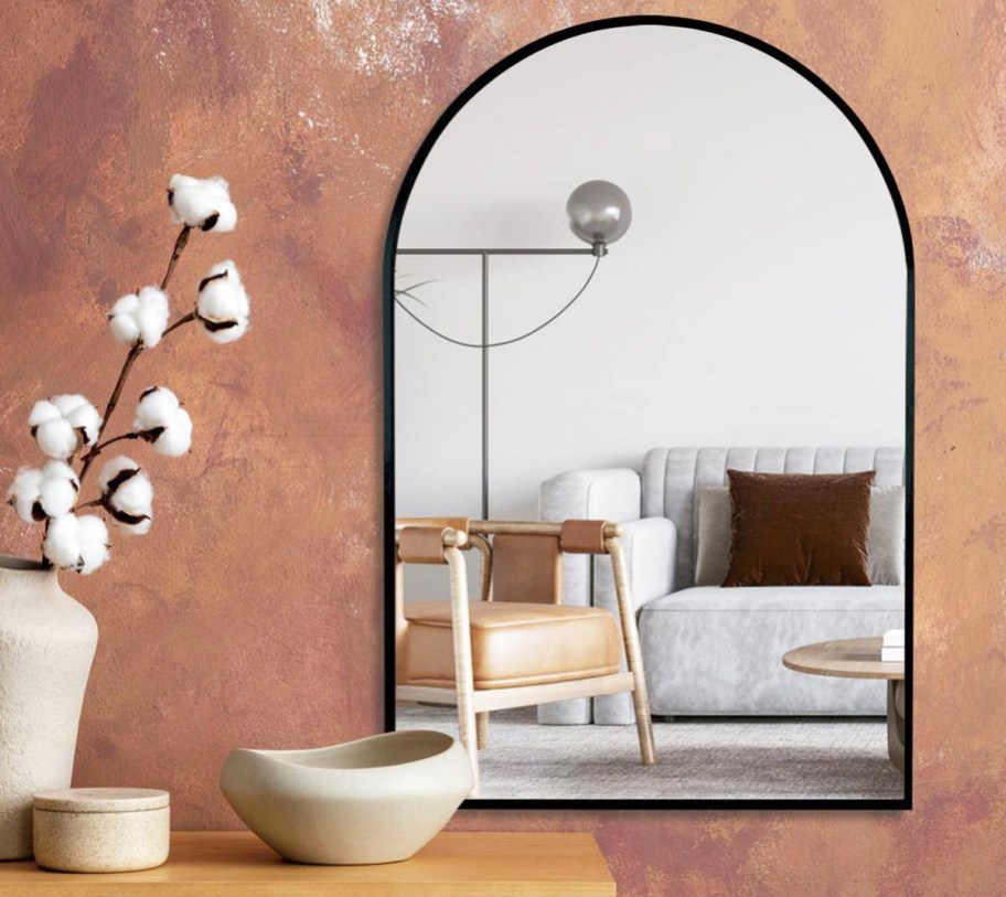 black framed arch mirror on a pink wall