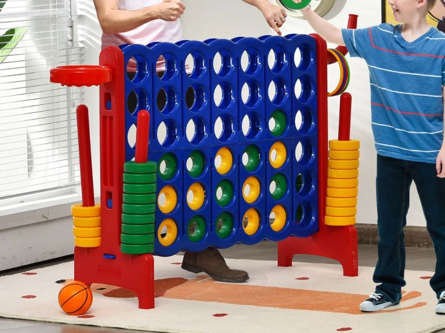 an adult and a child playing with a giant 4 in a row game