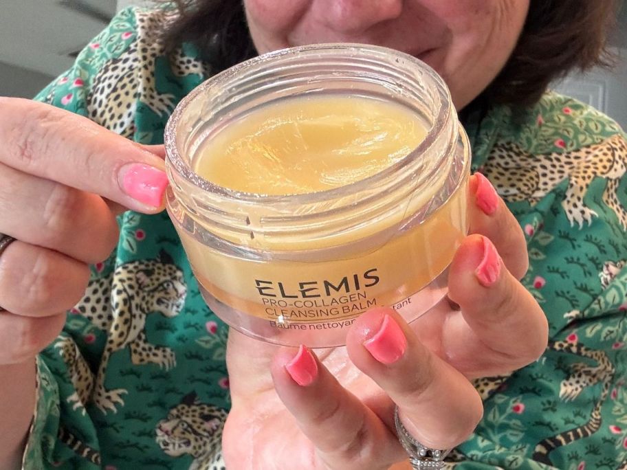 Woman holding an open jar of Elemis Cleansing balm