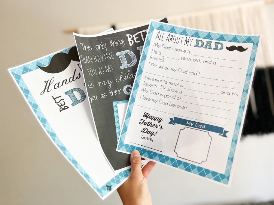 Hand holding three different Father's Day printable 