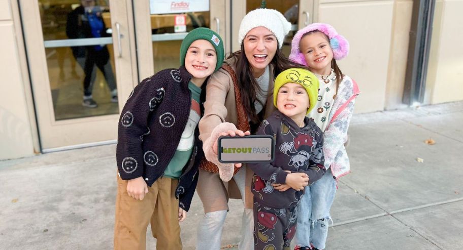 family in front of an ice rink holding a phone showing get out sign