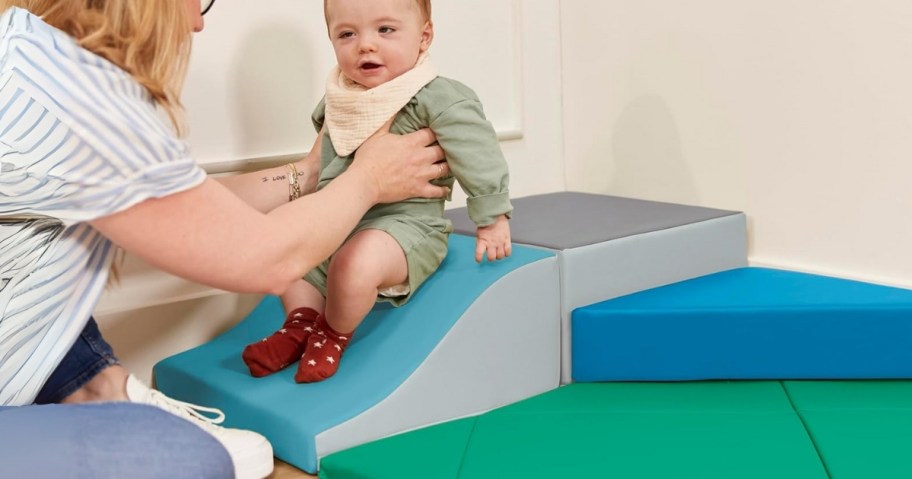 mom holding a baby on a climber playset