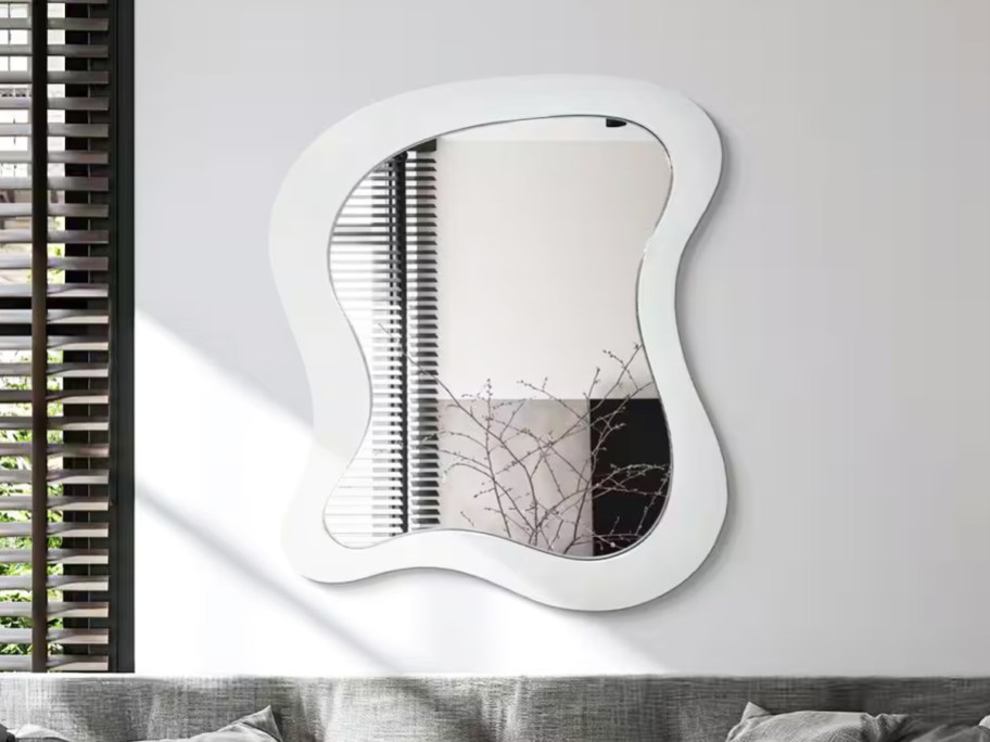irregular wavy white wood framed mirror on a wall