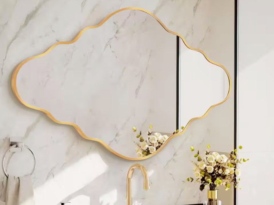 gold framed scalloped mirror on bathroom wall
