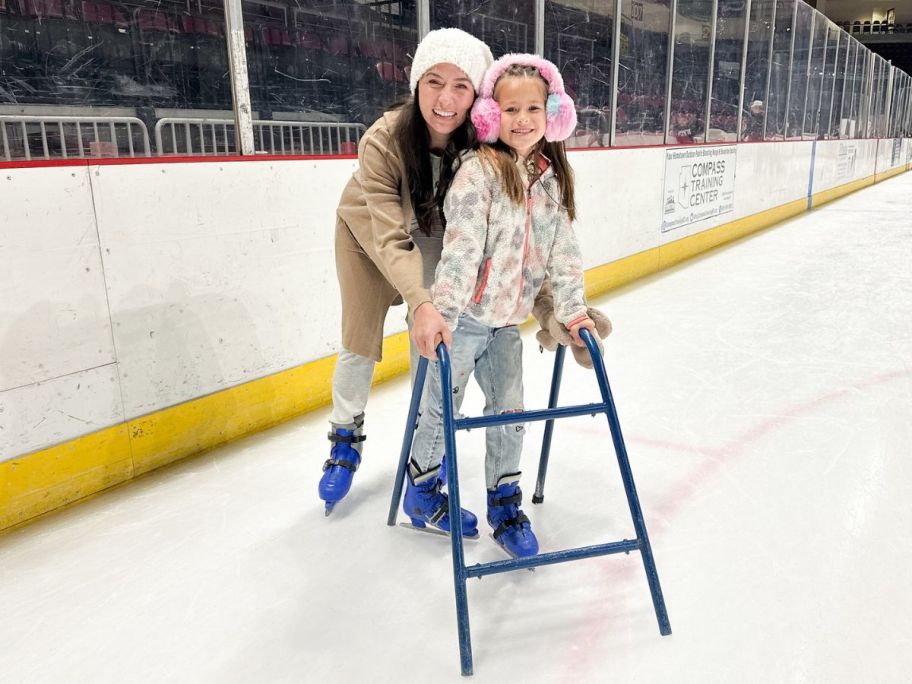 woman and child on an ice rink holding on 