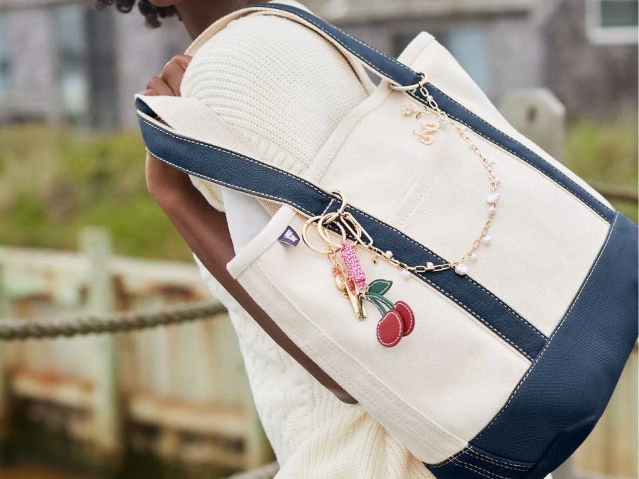 woman holding Lands end tote bag with cherry accessories on it 