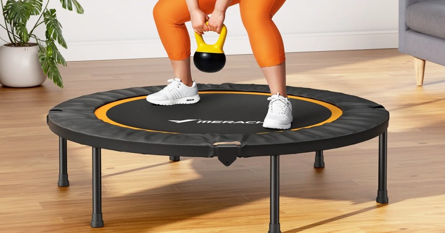 woman in orange leggings doing a squat on a mini trampoline