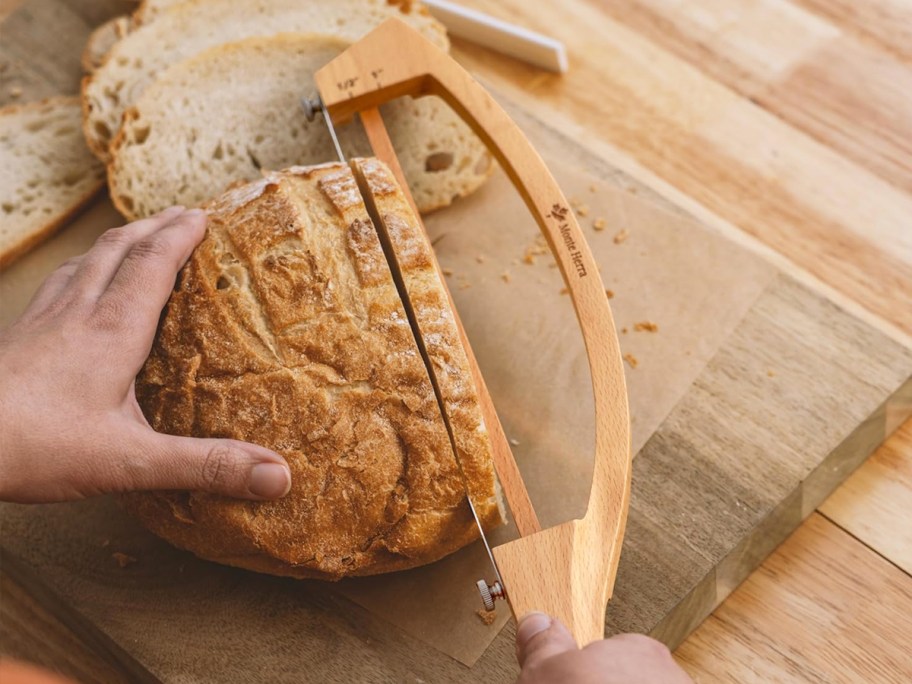 slicing a loaf of bread with a wood bread knife