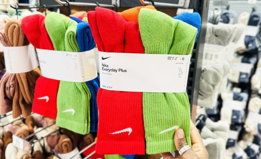 hand grabbing a set of colorful nike socks hanging on store display