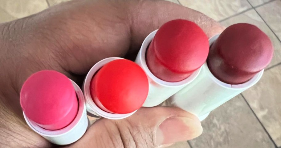 Woman holding 4 Nivea Fruity Cutie Tinted Lip Balms in her hands