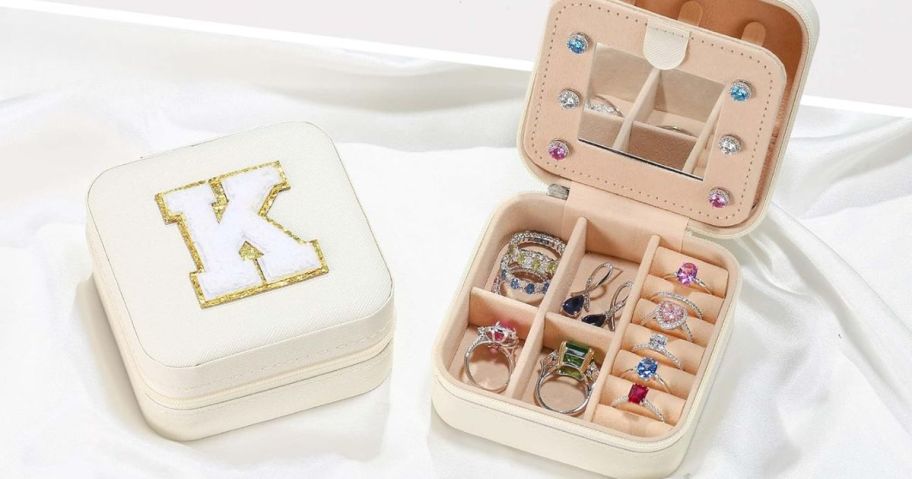 2 travel jewelry cases, one with the letter "K" on it and the other opened to display various pieces of jewelry