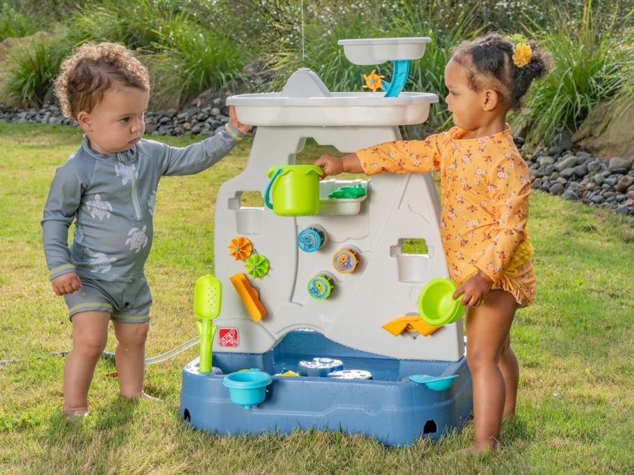 Kids playing with a large plastic toy water fountain 